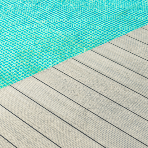 Gray-toned composite decking surrounding a pool with a bright light blue lining.